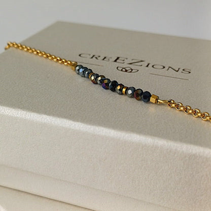 Goudkleurige RVS armband met zwarte facetkraaltjes met iriserende glans – elegant en verfijnd dames sieraad.