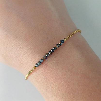 Goudkleurige RVS armband met zwarte facetkraaltjes met iriserende glans – elegant en verfijnd dames sieraad.