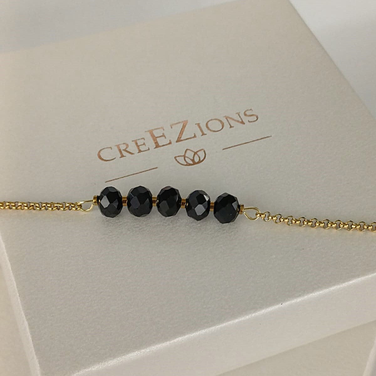 Goudkleurige RVS armband met zwarte facetkralen – tijdloze en minimalistische armband, ook verkrijgbaar in zilverkleur.