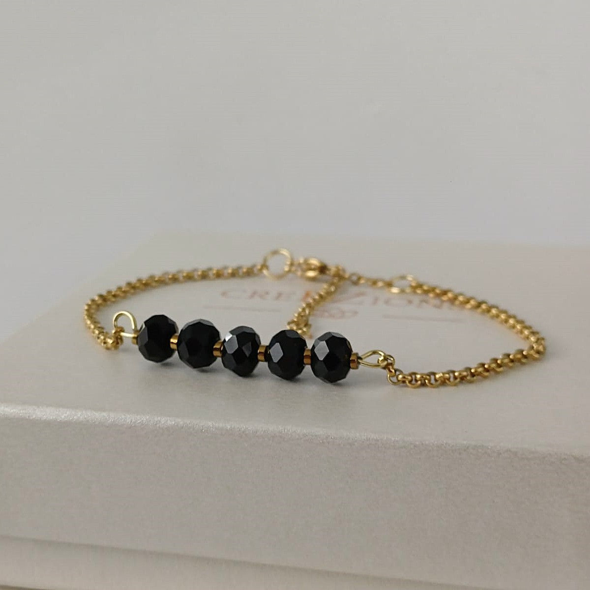 Goudkleurige RVS armband met zwarte facetkralen – tijdloze en minimalistische armband, ook verkrijgbaar in zilverkleur.