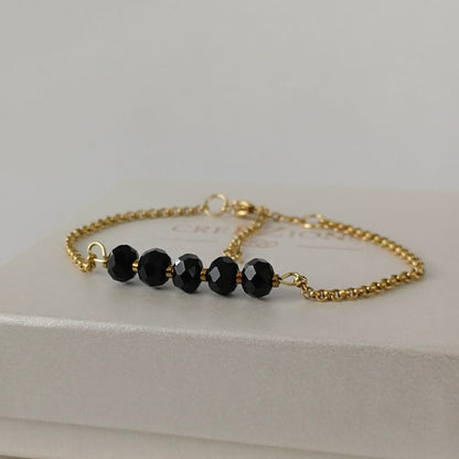 Goudkleurige RVS armband met zwarte facetkralen – tijdloze en minimalistische armband, ook verkrijgbaar in zilverkleur.