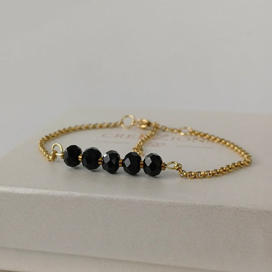 Goudkleurige RVS armband met zwarte facetkralen – tijdloze en minimalistische armband, ook verkrijgbaar in zilverkleur.