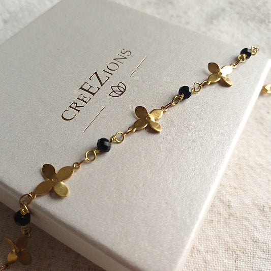 Messing armband met bloempatroon en zwarte facetkraaltjes – elegant & verfijnd